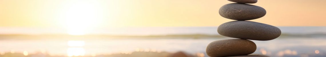 Zen stones balanced on the beach with copy space. Sunrise light. Meditation and relaxation.